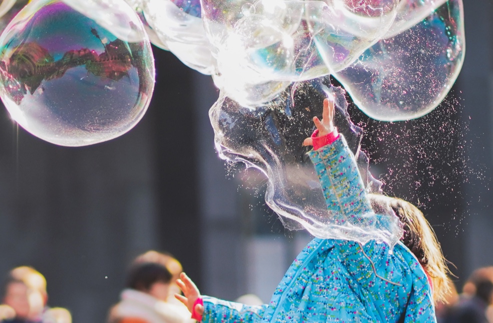 a young girl on a raincoat playing with bubbles